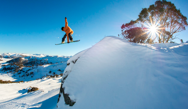 man snowboarding off a snowy cliff in Perisher