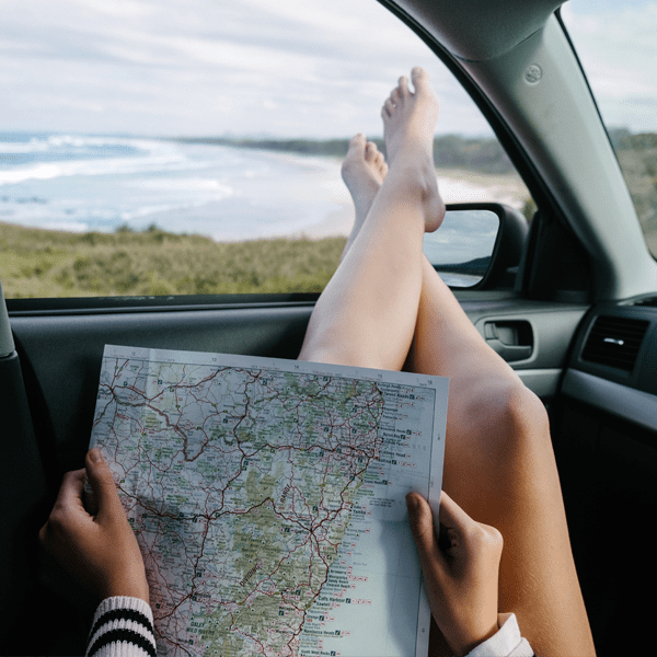 girl holding east coast Australia map with her feet hanging out of a car window