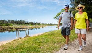 Two adults walking a long a river in Lakes Entrance