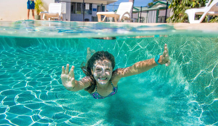 a young girl swimming underwater in a pool in a Bowen holiday park