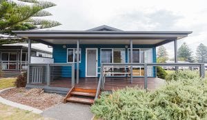 Blue cabin with deck inside a Shellharbour Holiday Park