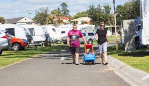 Mother and father walking child in a kids car through a Shellharbour caravan park