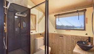 bathroom with shower, toilet and sink basin inside a glamping safari tent in Merimbula