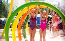 Two young girls playing inside colourful water feature at Splash Away Bay at NRMA Ocean Beach Holiday Resort