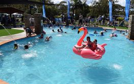 Kids swimming and two kids on a blow up flamingo in Splash Away Bay at NRMA Ocean Beach Holiday Resort