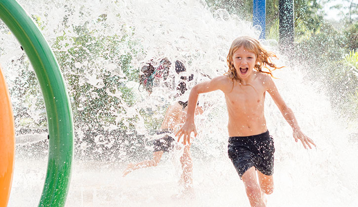 Young boy runnning through a water park at a Central Coast holiday resort